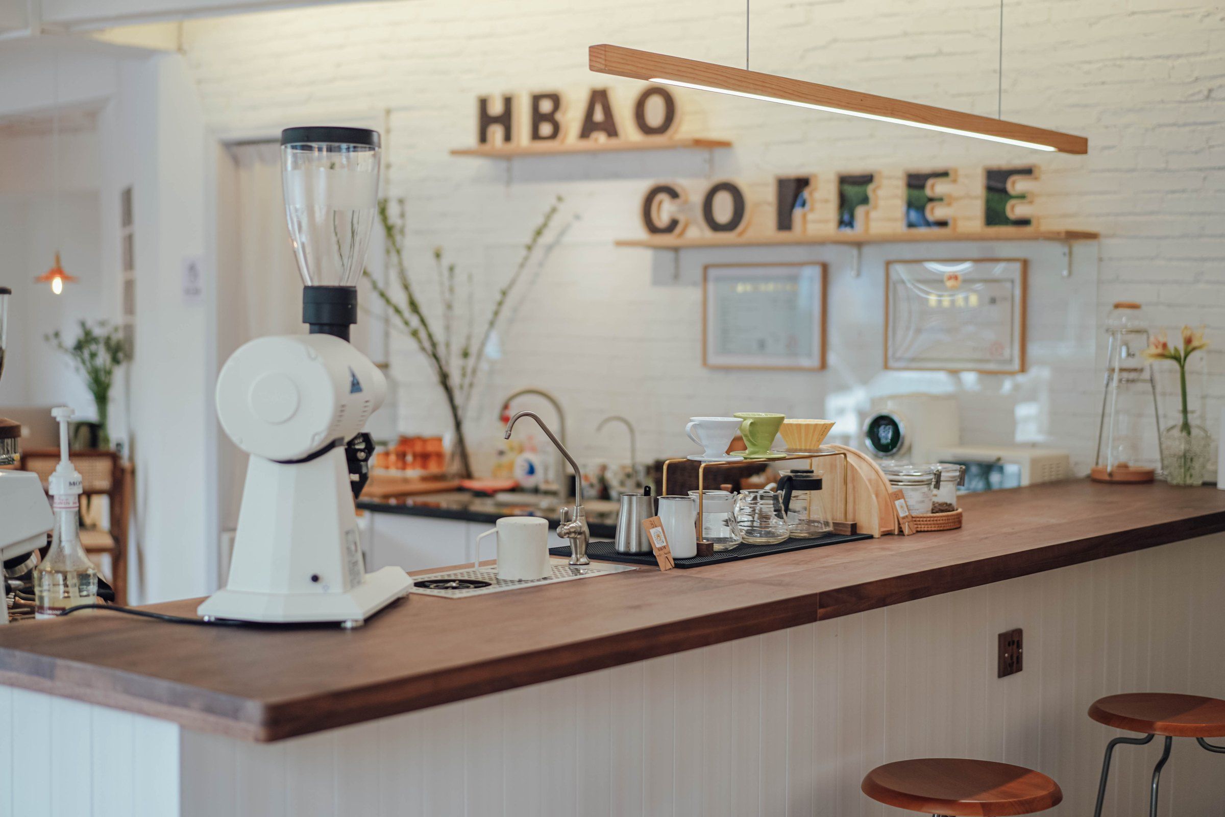 HBAO 木质吧台、磨豆机和写有 HBAO COFFEE 的白色墙面