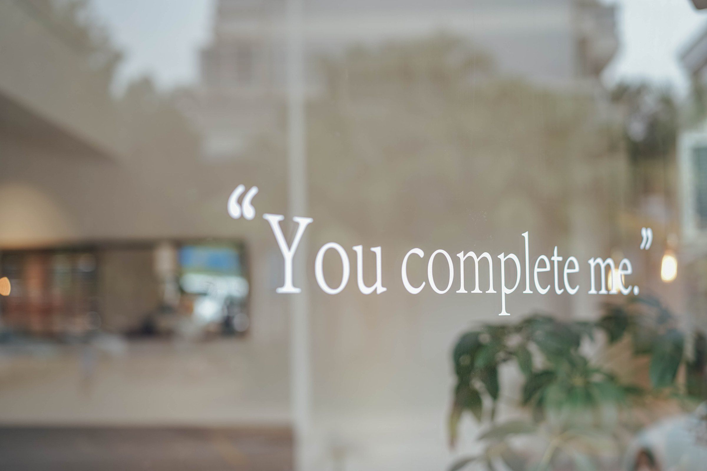 HBAO 窗玻璃上写着 You complete me,背景是模糊的室内空间